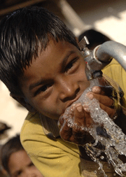 Boy drinking from tap in India