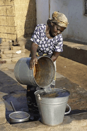Lady Pouring Water in Malawi - WaterAid/ Layton Thompson