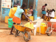 A child with a wheelbarrow at a water kiosk