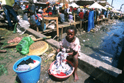 Girl washing clothes by dirty river